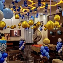 A complete room transformation for a baby boy's celebration. The entire ceiling is covered with blue, white, and gold balloons, creating a festive and immersive party environment.
