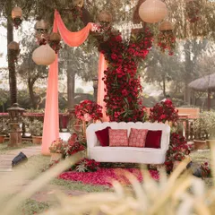 A romantic garden seating area. We decorated this tree with drapes and an abundance of red flowers, creating a beautiful and intimate photo corner for the couple.