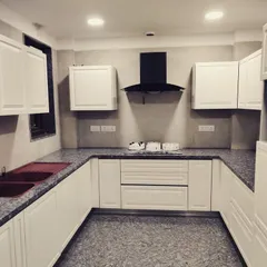 Here is a finished kitchen from a large 600 sq. yd. project in DLF Phase V, Gurgaon. It features classic white shaker-style cabinets, a durable granite countertop, and a functional U-shaped layout designed for heavy daily use.