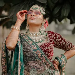 A bride with attitude. This fun and stylish portrait shows the bride in her full traditional glory, playfully adjusting her sunglasses.