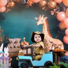 Ready for a jungle expedition, this little explorer sits in a toy jeep surrounded by friendly animal props like a giraffe and teddy bears.