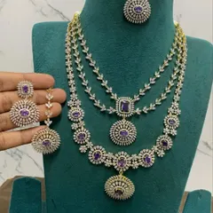 This layered necklace set features purple stones and a brilliant CZ diamond finish. It includes a choker, a mid-length necklace, and matching earrings.
