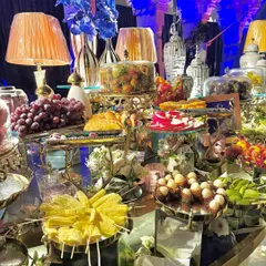 A lavish grazing table featuring an abundance of desserts and fresh fruits. This stunning display includes cakes, pastries, fruit skewers, and exotic fruits like rambutan and dragon fruit.