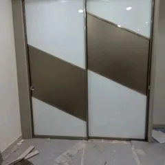 A custom Aristo wardrobe with a bold diagonal design on its sliding doors, combining white and bronze panels for a unique and contemporary look.
