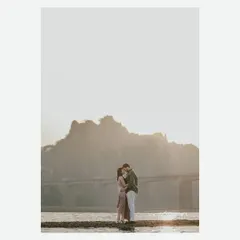 A minimalist and powerful silhouette of a couple against the setting sun and a distant bridge, capturing the intimacy of their connection in a vast landscape.
