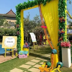 A cheerful and welcoming entrance for a Haldi function. The bright yellow arch, decorated with greenery and marigold garlands, sets a festive tone right from the start.