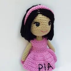 A closer look at the personalized doll I made, named Pia. You can see the embroidered name on her dress and the little headband, details that make each doll unique.