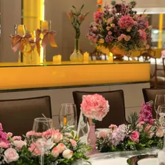 The tablescape featured a runner of delicate pink and purple flowers, with single pink peonies in minimalist vases. This created a soft, romantic atmosphere for the guests' dining experience.