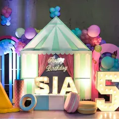 Welcome to Candyland. This delicious-looking stage features giant ice cream props, a candy-striped tent, and personalized marquee letters for a sweet-themed birthday.