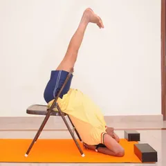 Viparita Karani using a chair. This variation provides a deeper backbend and opening of the chest compared to performing it only against a wall.