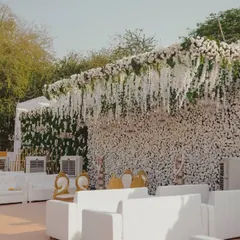 An all-white theme creates a look of pure elegance. This stage design features a wall of white carnations and cascading wisteria, complemented by modern white lounge seating, ideal for a high-end corporate party or brand launch.