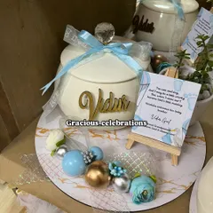 A close-up of our personalized baby announcement platter. This one features an elegant ivory handi for sweets like rasgulla or panjeeri, a live plant, and a custom card on a mini easel, all personalized with the baby's name.