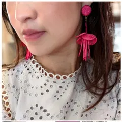 A model shot of the fuchsia floral beaded drop earrings, adding a vibrant pop of colour to a white lace top.