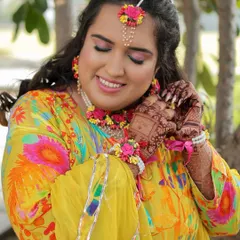 A candid shot of the bride admiring her floral jewellery. The soft, glowing makeup looks beautiful in the natural daylight.