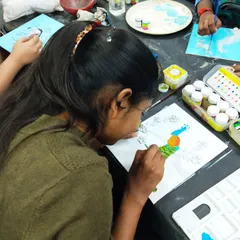 A participant painting a clay peacock mural. These workshops guide you from sculpting the base design to adding the final touches of color.