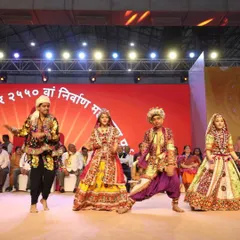 A troupe of folk dancers in vibrant traditional attire performing on stage for the Lord Mahavir foundation day event. We provide authentic cultural performers for religious festivals and community celebrations.