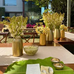 The beautiful outdoor setup for the Sadya lunch, with long tables adorned with traditional flowers and banana leaf place settings.
