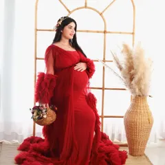 A beautiful portrait in a vibrant red ruffled gown. The mom-to-be is posed in our studio's window arch set, complete with pampas grass and a flower basket for a rustic touch.