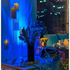 I used dramatic blue uplighting to create a cool, evening mood in this corner, contrasting with the warm glow of the pillar candles. A basket of fresh lemons adds a pop of color and fragrance.