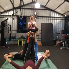 This three-person pose requires balance from everyone involved. The student on top holds a prayer pose while being supported by her teammates, a common exercise in our acro-yoga sessions.