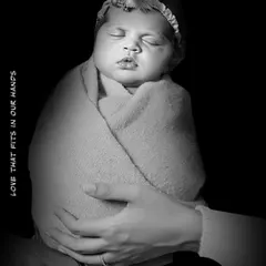 A dramatic black and white photo showing a mother's hands wrapped around her sleeping baby. The caption "Love that fits in our hands" perfectly describes this precious, tiny stage.