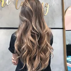 This shimmery, golden blonde balayage gives off perfect summer vibes. The long, flowing waves are full of dimension, creating a stunning look that is both bright and natural.