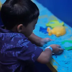 Our sensory sand pit offers a clean and creative play experience. Here, a young child is using molds to create shapes, which is great for developing fine motor skills.