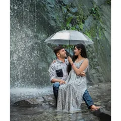 A romantic moment under an umbrella by a waterfall. The cascading water adds a dynamic and refreshing element to this intimate pre-wedding portrait.