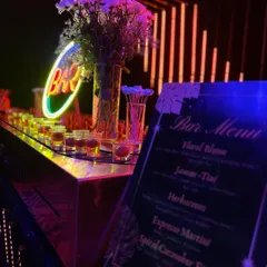 This neon bar setup features a custom menu with cocktails like 'Floral Bloom' and 'Espresso Martini', all served under dramatic LED lighting.