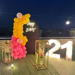 A similar 21st birthday setup on an artificial grass surface, showing the neon sign, marquee numbers, and balloon arrangement against the night sky.