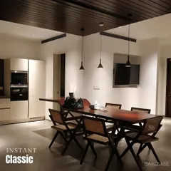 This dining area is an instant classic. We combined a dark wood dining table with woven cane chairs and minimalist pendant lights against a dark wood-paneled ceiling to create a sophisticated and timeless look.