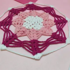 A different angle of the doily, showing the delicate, web-like strands that connect the central flower motif to the outer border.