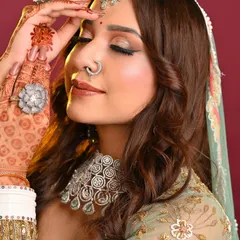 A soft and elegant Mehendi or Sangeet look by an MBM student. The focus is on glowing skin, a subtle bronze eye, and defined brows, perfectly complementing the diamond jewelry and pastel green outfit.