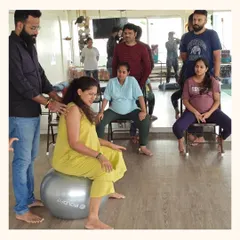 A guru provides hands-on guidance to an expectant mother using a stability ball. These sessions are designed to improve pelvic mobility and ease discomfort, preparing the body for a smoother birth.