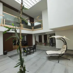 A view within the courtyard, showcasing the juxtaposition of different volumes and levels. This open area serves as a tranquil indoor garden and lounge, promoting natural air circulation and a peaceful atmosphere.