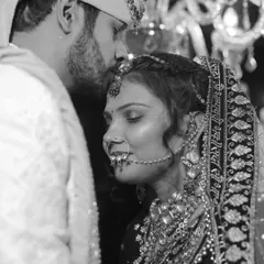 A powerful and emotional black and white close-up. The groom's tender kiss on the bride's forehead is a timeless expression of love and protection, captured beautifully.