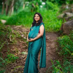 A solo portrait of a mother-to-be in a beautiful green saree, standing on a rustic path. We use natural surroundings to frame our subjects, creating a serene and timeless feel for your maternity photos.