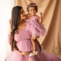 A heartwarming maternity photo capturing a mother and daughter sharing a happy moment before the new baby arrives. Their matching dresses are lovely.