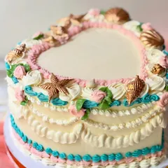 An elegant, vintage-style heart-shaped cake. I used various piping techniques to create intricate ruffles and borders, and decorated it with golden, edible seashells.