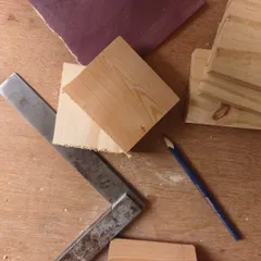 Every creation starts with raw materials and an idea. Here, pieces of solid pine wood, a pencil, and a square are ready to be transformed into something beautiful.