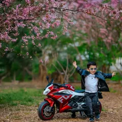 Capturing the adventurous spirit of a toddler is pure joy. This outdoor portrait session uses a fun toy motorcycle prop and the beautiful backdrop of spring blossoms to tell a story of childhood freedom and play.