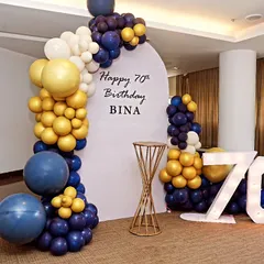 Celebrating 70 and fabulous! This simple and elegant coustamised decor for a 70th birthday features a modern arched backdrop and a stylish balloon arrangement in mustard yellow and blue.
