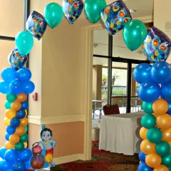 An entrance arch for a Krishna-themed party, using blue, green, and orange balloons, peacock feather foil balloons, and a Krishna cutout.