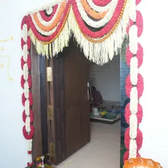 Traditional floral decor for the main door of the house. We used garlands made of red and white flowers to create an intricate and welcoming entryway for the Griha Pravesh ceremony.