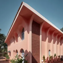 The architecture of Baia Villas is defined by its bold forms and playful use of color. This exterior view showcases the interplay of arches and a terracotta jali screen, elements that nod to Goan heritage while creating a distinctly contemporary facade.
