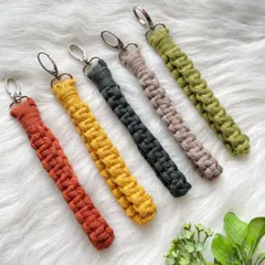 My practical and stylish macrame wristlet keychains, shown here in a palette of warm, earthy tones including rust, mustard yellow, charcoal, taupe, and olive green. The sturdy metal clasp keeps your keys secure while the soft strap fits comfortably around your wrist.