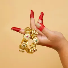 A pair of our traditional Kundan kadas, showcased by a classical dancer's hand. These bangles feature intricate work and colorful stones, perfect for festive and cultural events.
