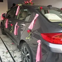 A simple and elegant car decoration using pink roses and ribbons on the doors and roof.