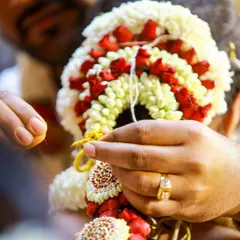 A close-up of a wedding ritual, focusing on the intricate floral garland being prepared.