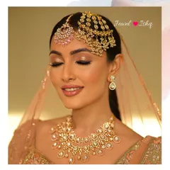 A soft, romantic bridal look featuring an uncut diamond Polki necklace and a delicate passa and maang tikka combination. The pastel pink stones add a modern touch to the traditional design.